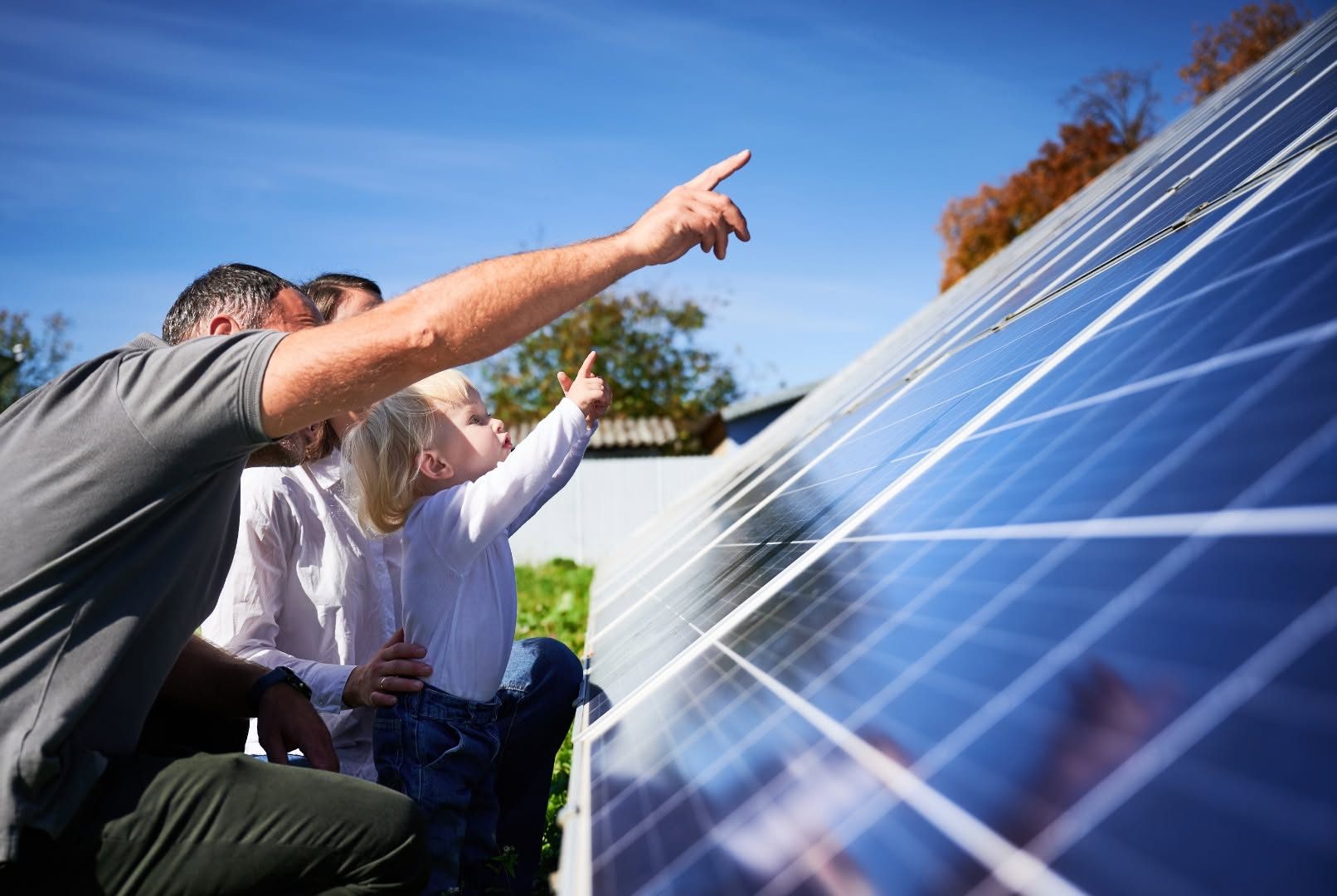 Familie zeigt begeistert auf eine Solaranlage im Garten